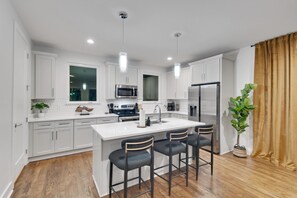 A modern kitchen with white cabinets, stainless steel appliances, and a central island with bar stools.