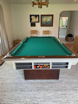 A pool table with a green felt surface, surrounded by a carpeted floor. - Atomic Acres- Pool, Hot tub, Fire pit & more (Sawyer)