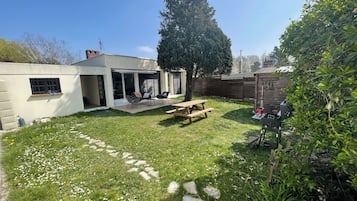 A backyard with a patio, a barbecue grill, and a wooden fence.
