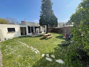 Un jardin avec une terrasse, un barbecue et une clôture en bois.