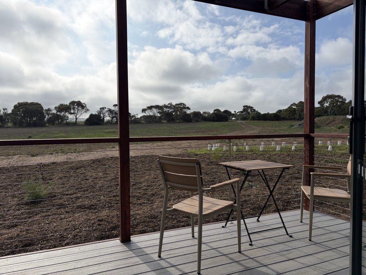 Une terrasse extérieure avec une table et des chaises, donnant sur un champ.