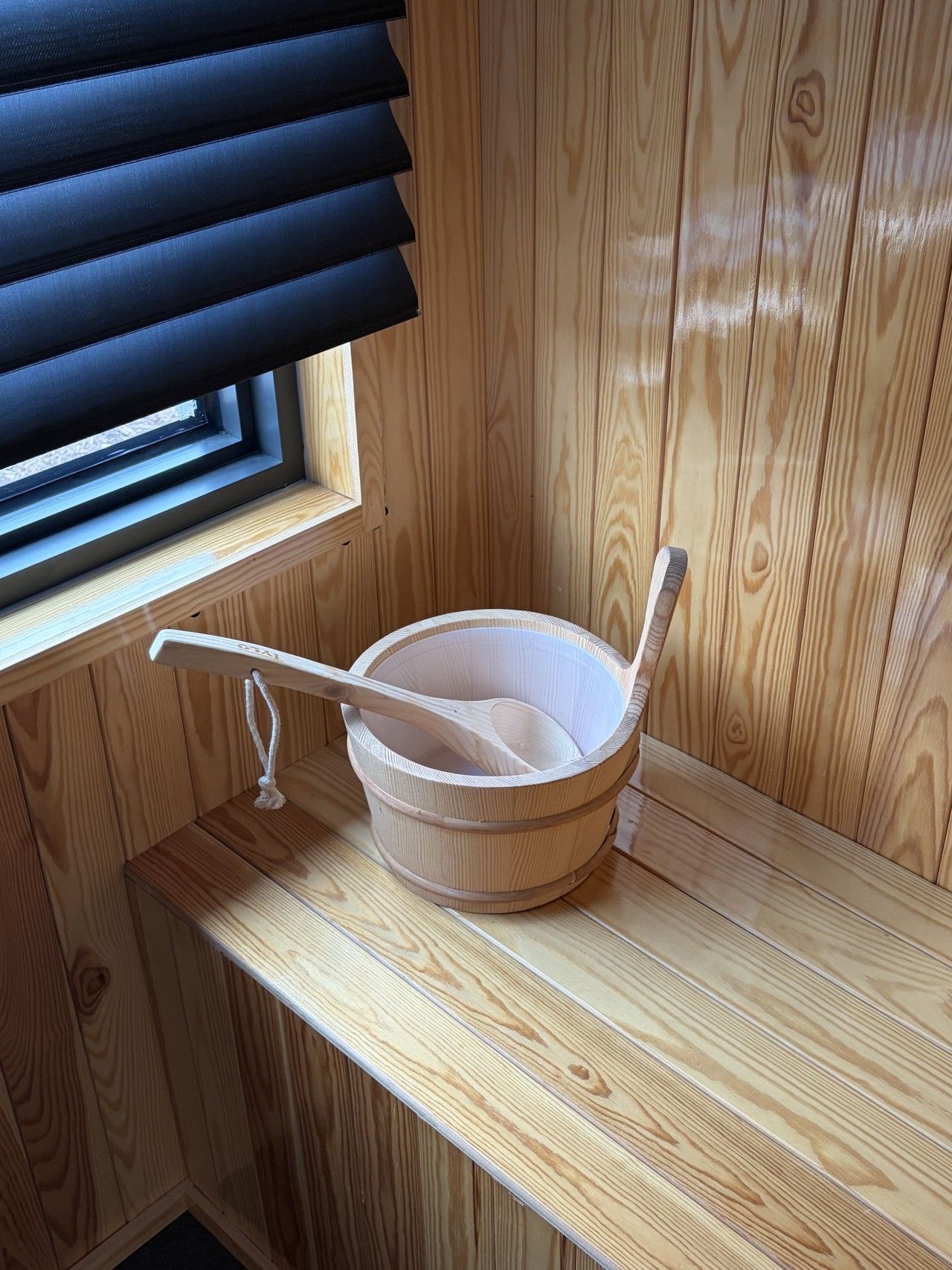 Un sauna en bois avec une baignoire en bois et une cuillère en bois posée sur le bord.