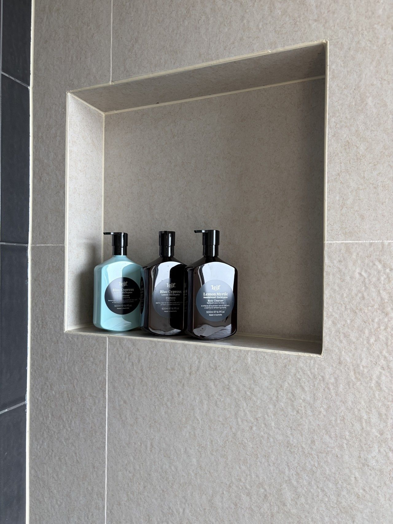 Une étagère de salle de bain avec trois flacons de produits de toilette.