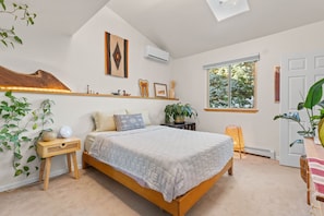 Une chambre à coucher comprenant un lit, des tables de chevet, une fenêtre et un climatiseur fixé au mur.
