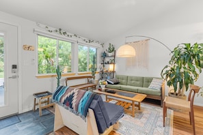 Un salon confortable avec un canapé, une table basse et une grande fenêtre.