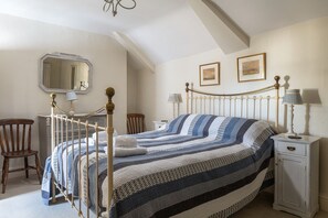 A bedroom with a four-poster bed, a wooden chair, a nightstand with a lamp, and a wardrobe. - Bwthyn Gwe Cottage in heart of St Davids (St Davids)