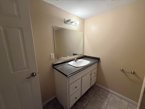 Une salle de bain avec un lavabo blanc, un miroir, une porte et un porte-serviettes.