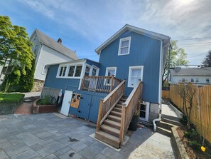 Une maison à deux étages, avec une façade bleue, un escalier en bois et une petite terrasse.
