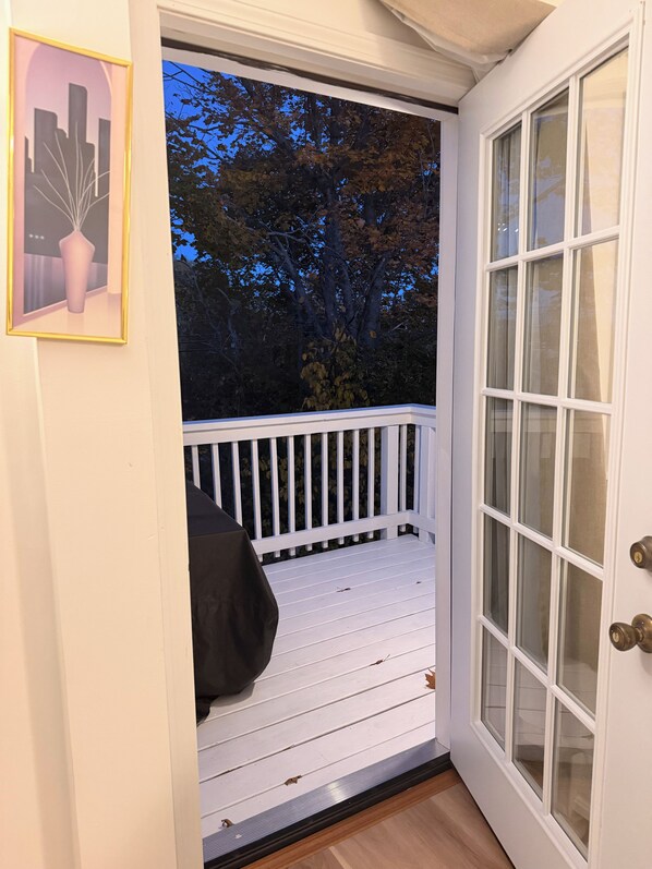 A white door with a glass panel, a white porch with a railing, and a framed picture on the wall.