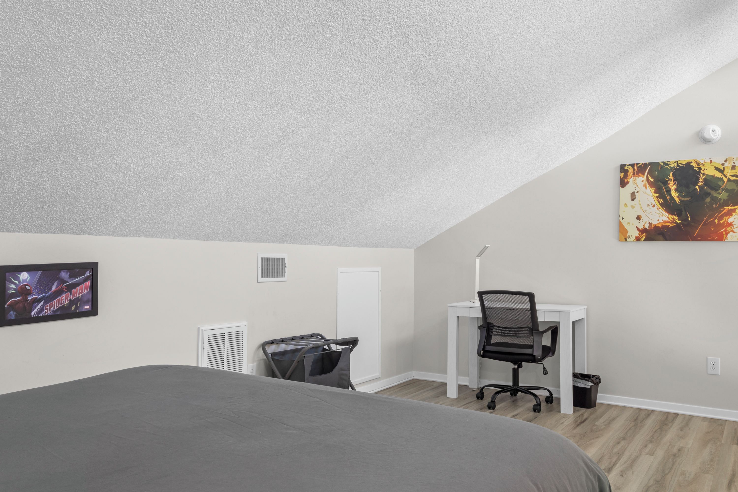 Une chambre à coucher comprenant un lit, un bureau, une chaise, un radiateur, une lampe fixée au mur et un tableau encadré.