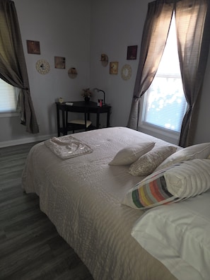 Een slaapkamer met een bed, een bureau en een raam met gordijnen.