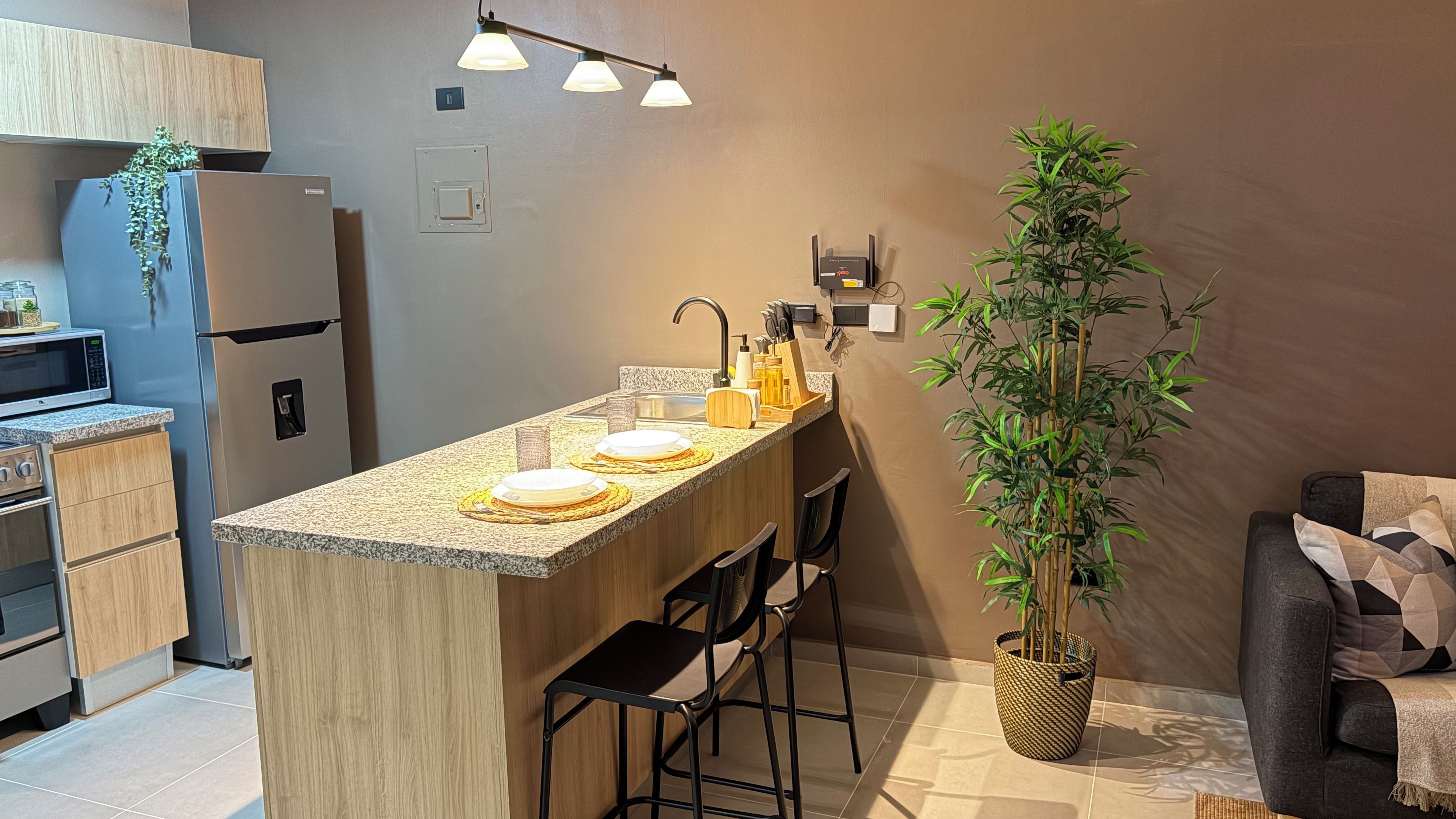 Une cuisine moderne dotée d’un îlot central, de tabourets de bar, d’un four à micro-ondes et d’un réfrigérateur.