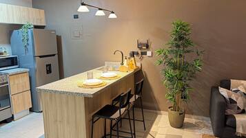 Une cuisine moderne dotée d’un îlot central, de tabourets de bar, d’un four à micro-ondes et d’un réfrigérateur.