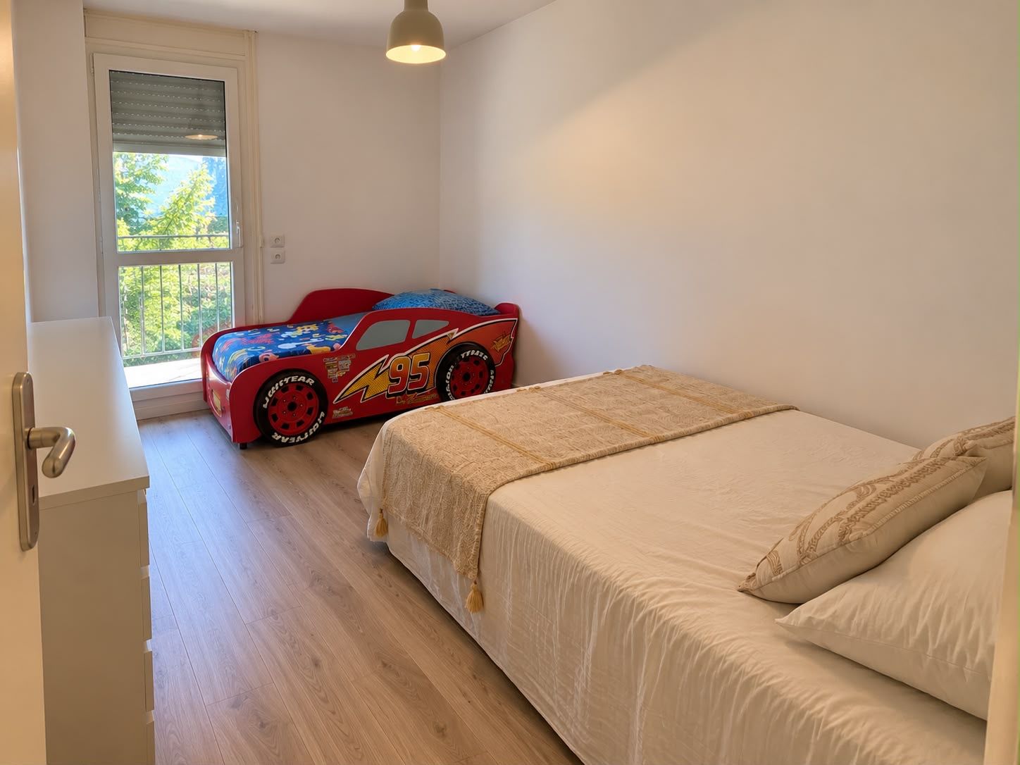 Une chambre à coucher avec un lit, une fenêtre et une voiture jouet.