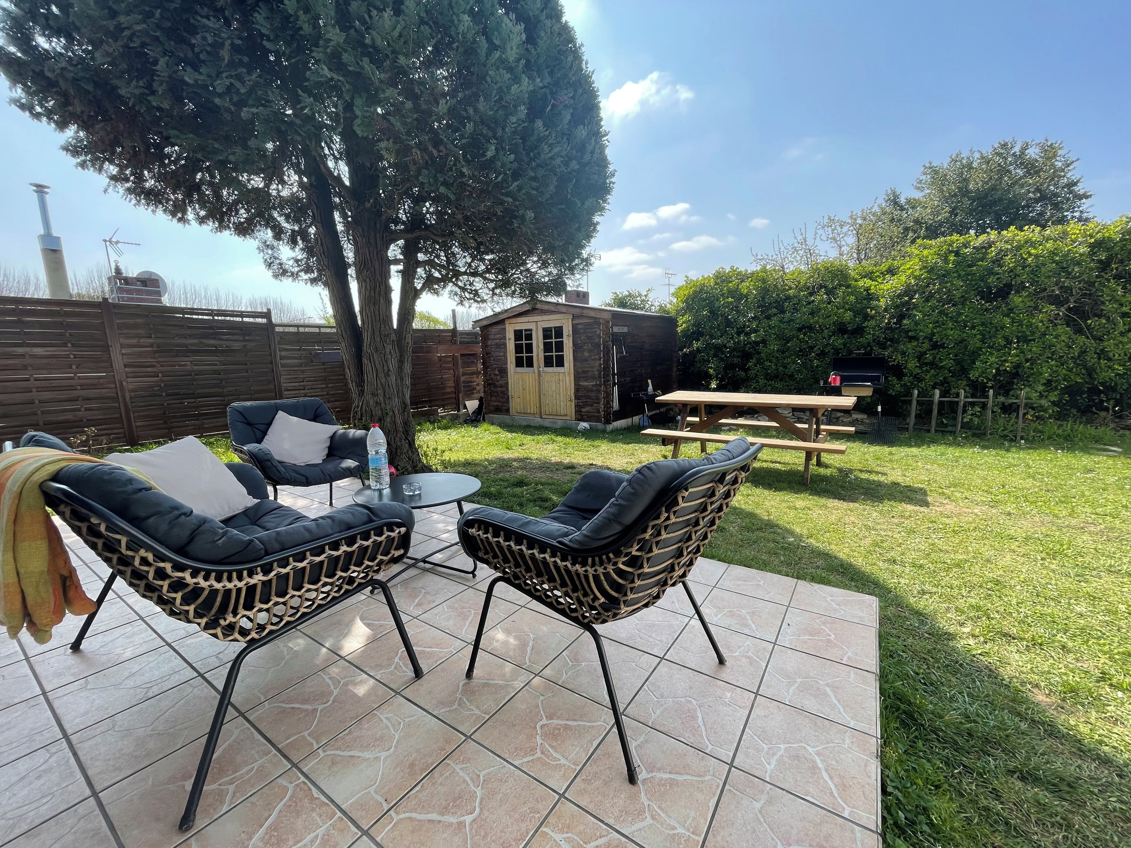 An outdoor patio with two chairs, a table, and a wooden bench.