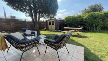 An outdoor patio with two chairs, a table, and a wooden bench.