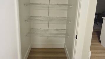 Un placard blanc avec trois étagères en fil de fer et un plancher en bois.