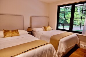 Een hotelkamer met twee bedden, een raam met uitzicht op groen en een houten vloer.