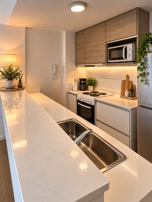 A modern kitchen with stainless steel appliances, a wooden cabinet, and a countertop with a sink. - CANNIG CENTER  (Canning)