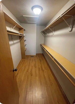 Un petit dressing étroit avec un plancher en bois, des étagères intégrées et un luminaire au plafond.