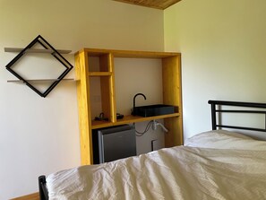 A bedroom with a bed, a wooden desk with a black sink, and a wall-mounted shelf. - Beachside properties hotel (Miami Beach)
