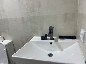 A bathroom with a white sink, a modern faucet, and a toilet. - Beachside properties hotel (Miami Beach)