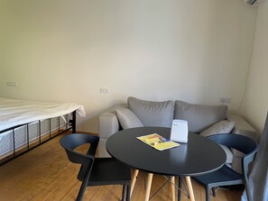 A small, furnished room with a bed, a sofa, a round table, and two chairs. - Beachside properties hotel (Miami Beach)