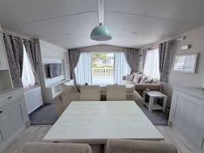 En moderne og veloplyst opholdsstue med spisebord, sofaer og fjernsyn.