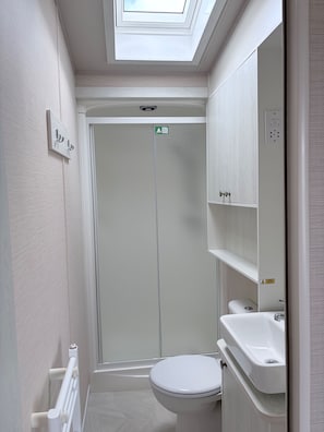 A bathroom with a skylight, a toilet, a sink, and a shower enclosure. - Ambleside Lodge Sleeps 6 with Parking and Wrap Around Balcony (Porthmadog)
