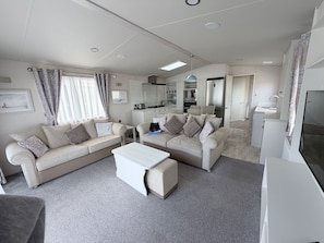 A modern living room with two sofas, a coffee table, and a TV. - Ambleside Lodge Sleeps 6 with Parking and Wrap Around Balcony (Porthmadog)