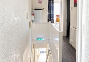 A narrow hallway with a white wall, a door at the end, and a small window. - 1 Bed Flat Sleeps 2 - Pets Welcome - Tv & WiFi (Middlesbrough)