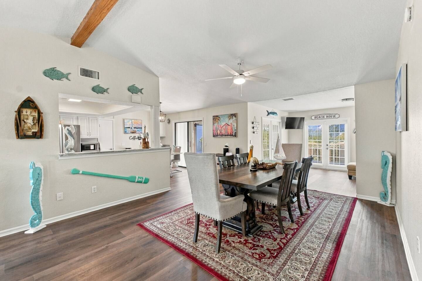 A spacious dining area with a large wooden table, chairs, and a red patterned rug.