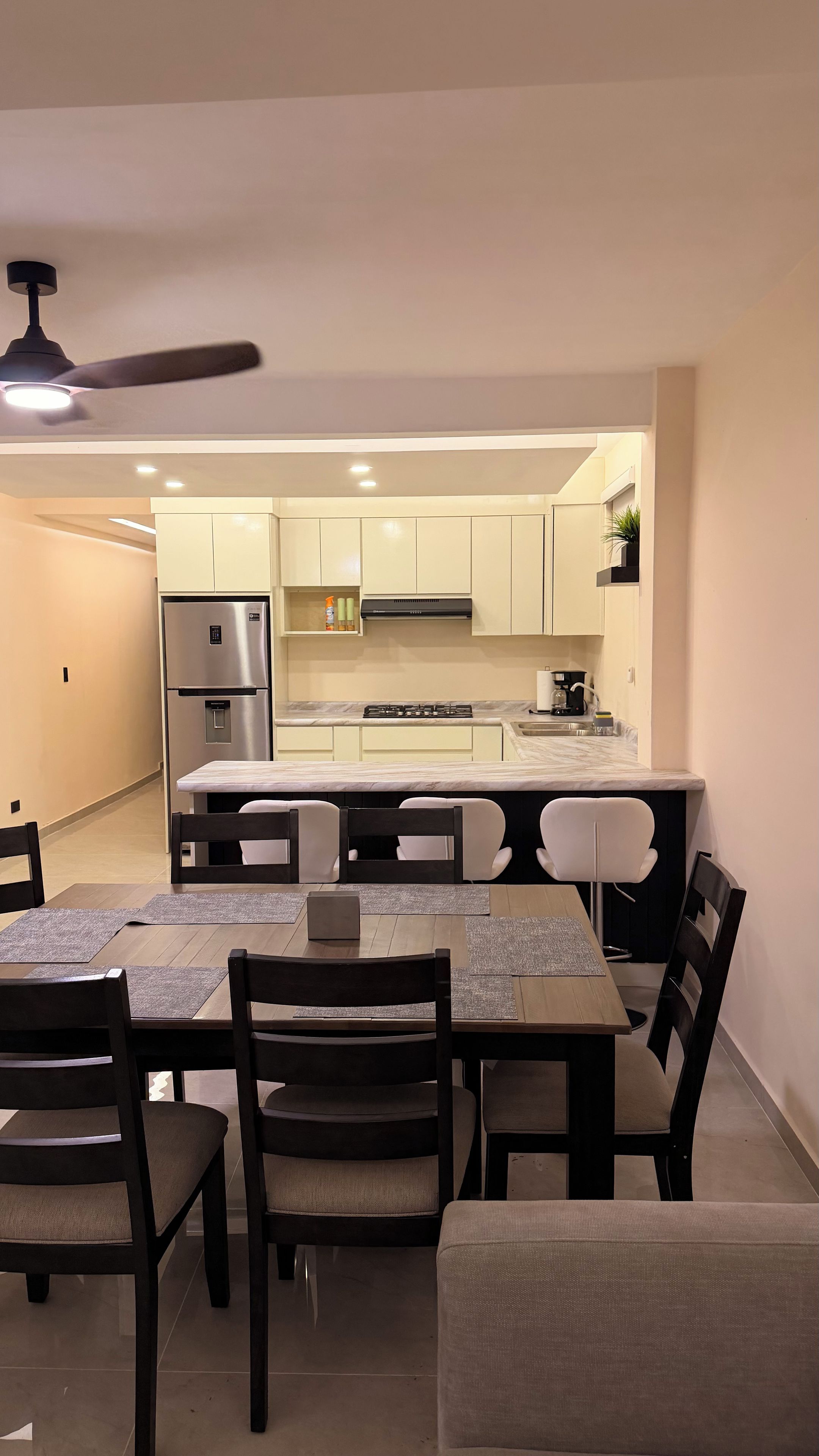A modern kitchen with a built-in refrigerator, stove, and microwave. There is a dining area with a table and chairs.