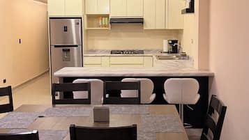 A modern kitchen with a built-in refrigerator, stove, and microwave. There is a dining area with a table and chairs.