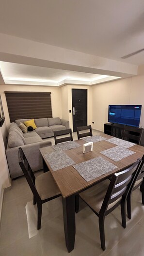 A modern living room with a sofa, a dining table, and a TV. - New Listing (Ensenada)