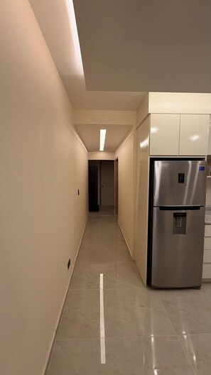 A corridor with a stainless steel refrigerator and a door at the end. - New Listing (Ensenada)