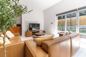 Ein modernes Wohnzimmer mit einer Sofaecke, einem Fernseher und einem Essbereich.
