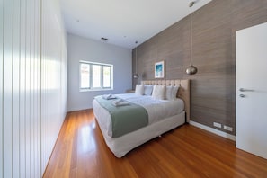 Ein Schlafzimmer mit einem großen Bett, einem Fenster, einer Tür und einer Holzwand.