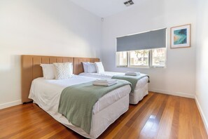 Quarto de hotel com duas camas, uma janela grande com vista e um quadro na parede.