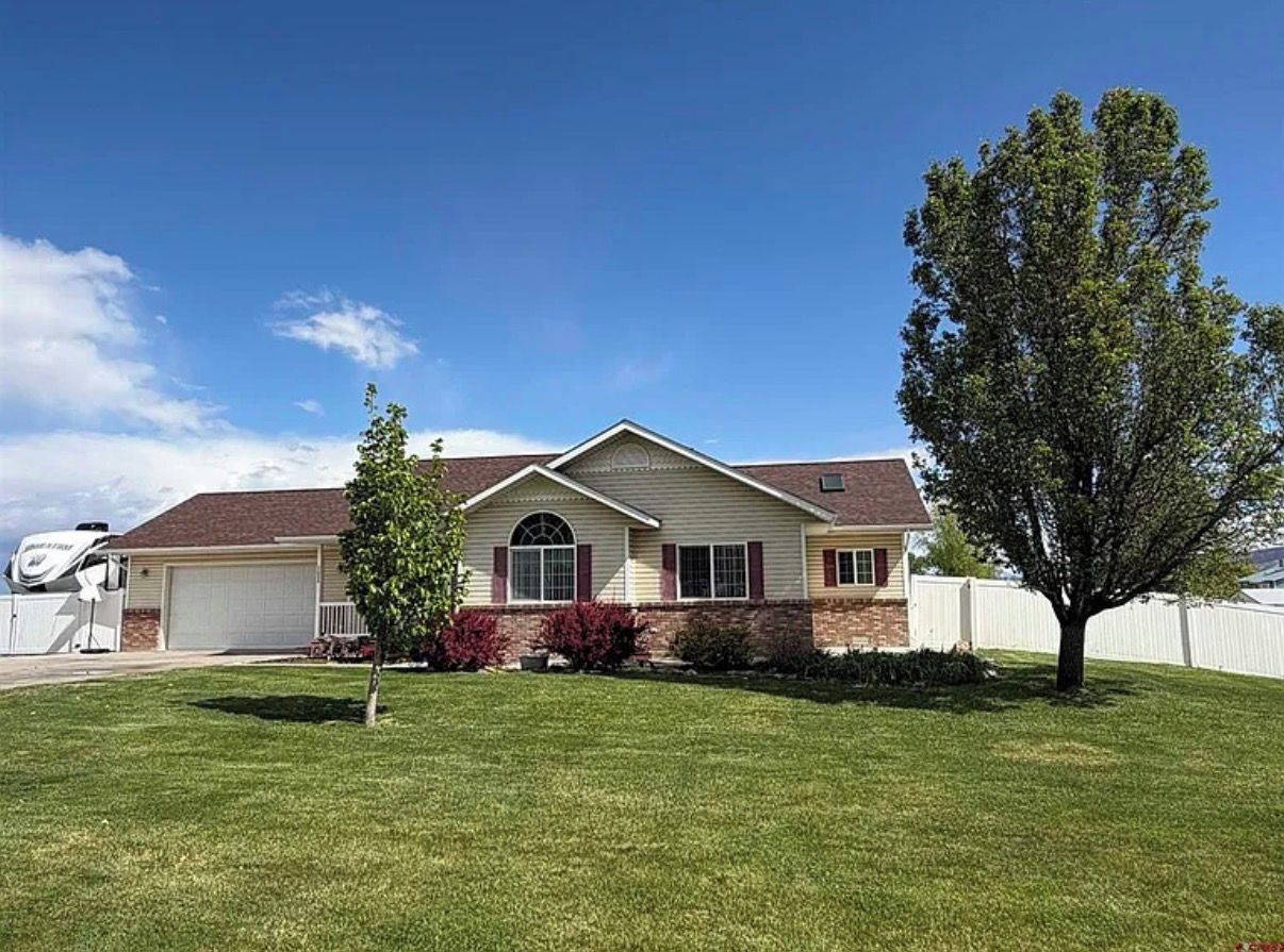 A single-story house with a garage, a lawn, and a tree.