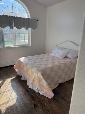 Une chambre à coucher avec un lit, une fenêtre avec des rideaux et une vue sur l’extérieur.