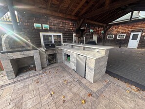 Un espace cuisine extérieur comprenant un barbecue, un four encastré et un plan de travail.