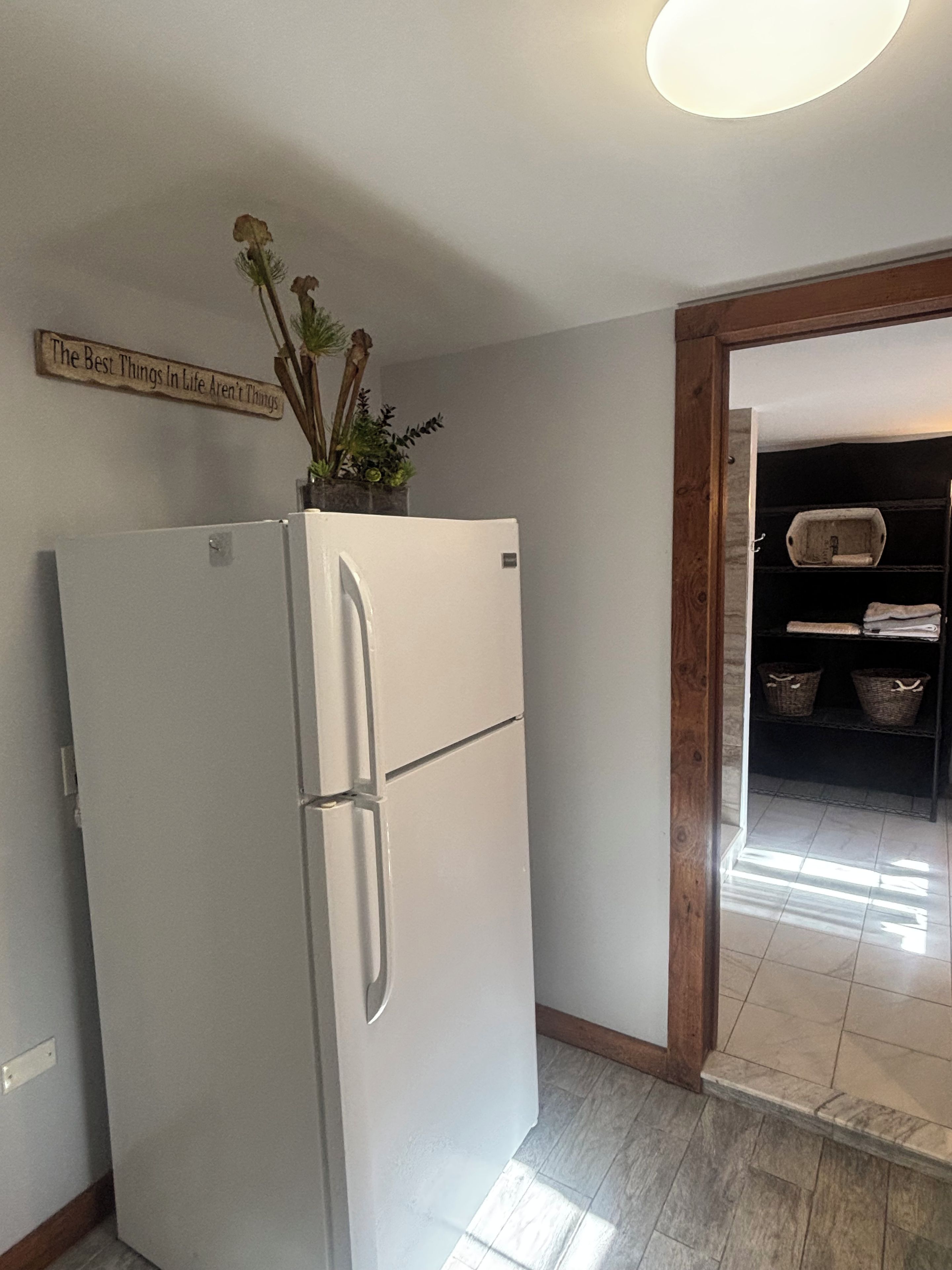 Une cuisine avec un réfrigérateur blanc, un chambranle de porte en bois et un panneau fixé au mur.