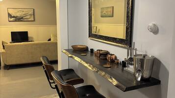 Une cuisine moderne avec un coin bar, des tabourets de bar, un grand miroir et une machine à café.