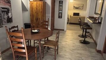 Un coin repas avec une table ronde, des chaises en bois, un ventilateur de plafond et un mur en briques.