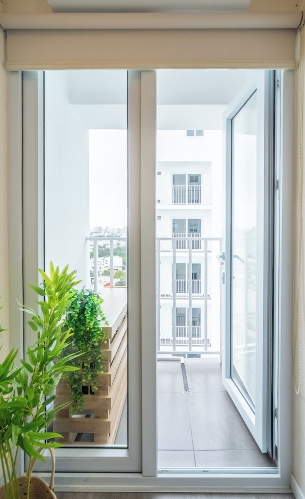 Ein Balkon mit Blick auf ein Gebäude, einer Topfpflanze und einem Metallgeländer.
