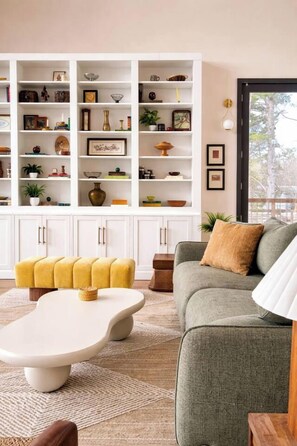 Ein Wohnzimmer mit einer Couch, einem Couchtisch und einem Bücherregal voller Gegenstände.
