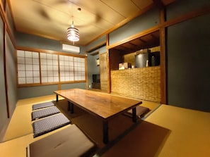 Una tradizionale stanza giapponese con pavimentazione in tatami, un tavolino in legno, porte scorrevoli e un angolo cottura con un fornello.