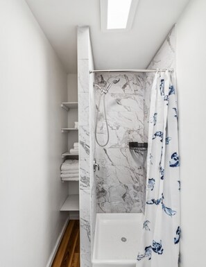 A shower with a marble wall, a showerhead, and a curtain with a blue pattern. - Bryn Mawr 1st Floor Apartment / Near Villanova (Bryn Mawr)