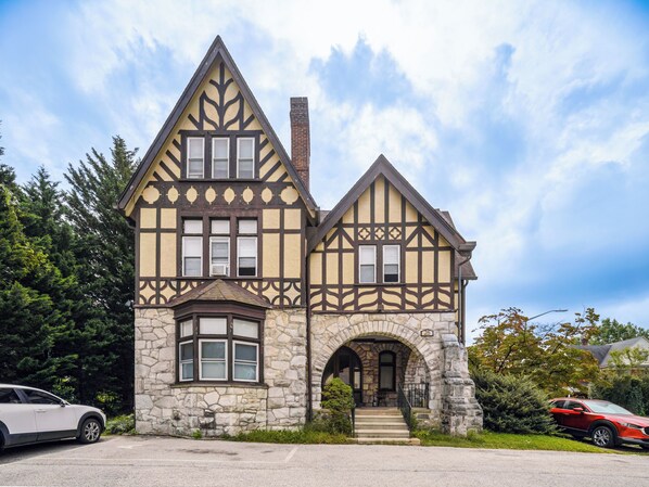 A two-story Tudor-style house with a stone facade, multiple windows, and a chimney. - Bryn Mawr 1st Floor Apartment / Near Villanova (Bryn Mawr)